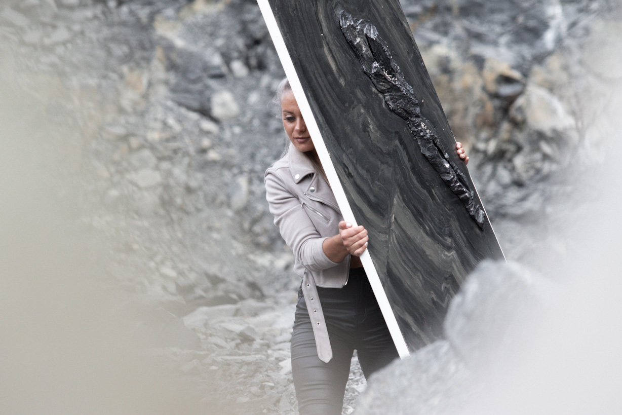 Die Künstlerin Jennit trägt im Steinbruch ein großes Werk ihrer Kunstserie Marbleous